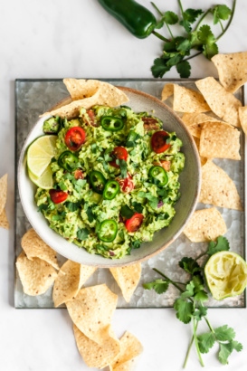 the best guacamole in a white bowl next to tortilla chips