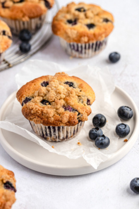 bakery style blueberry muffin on a plate with blueberries