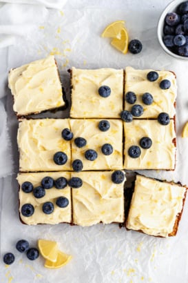 healthy lemon blueberry zucchini cake cut into nine slices topped with frosting