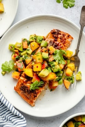 firecracker salmon on a plate topped with peach salsa