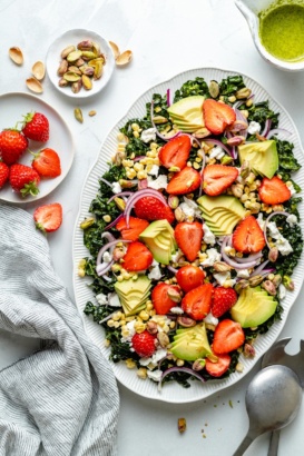 summer kale salad on a platter with strawberries and avocado