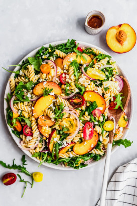 arugula pasta salad with peaches in a bowl
