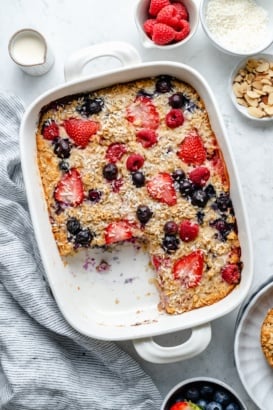 berry baked oatmeal in a baking dish with a slice cut out